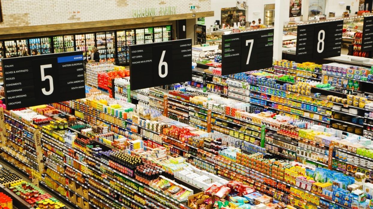 A birds-eye view of multiple grocery store aisles and numbered signs above them indicateingwhat food items are shelved in each aisle.