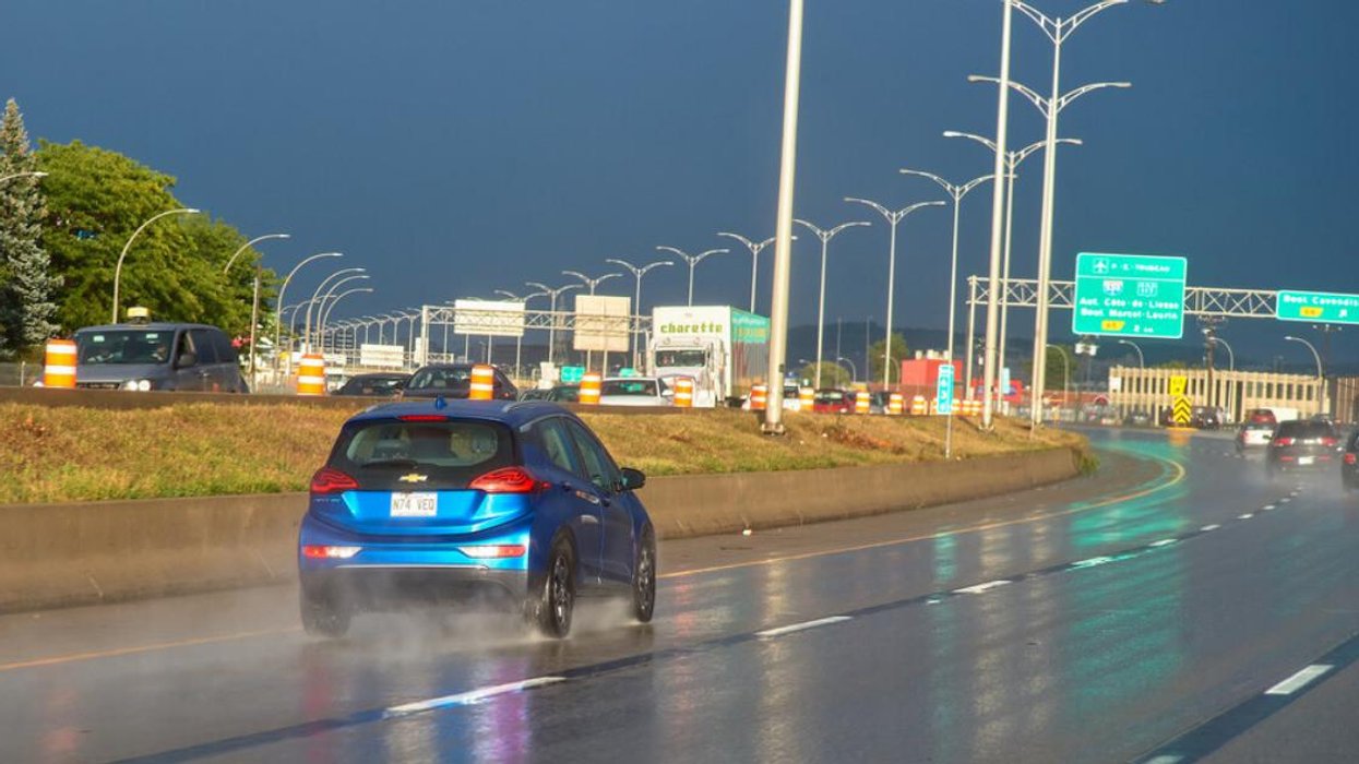 A blue Chevy kicks up water on a Montreal highway after a heavy rain.