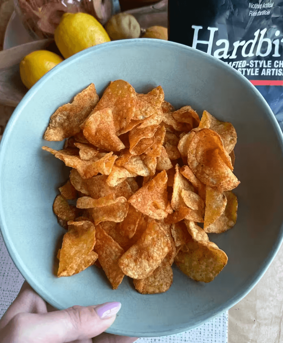 A bowl of Hardbite smoky BBQ potato chips next to a Hardbite bag.