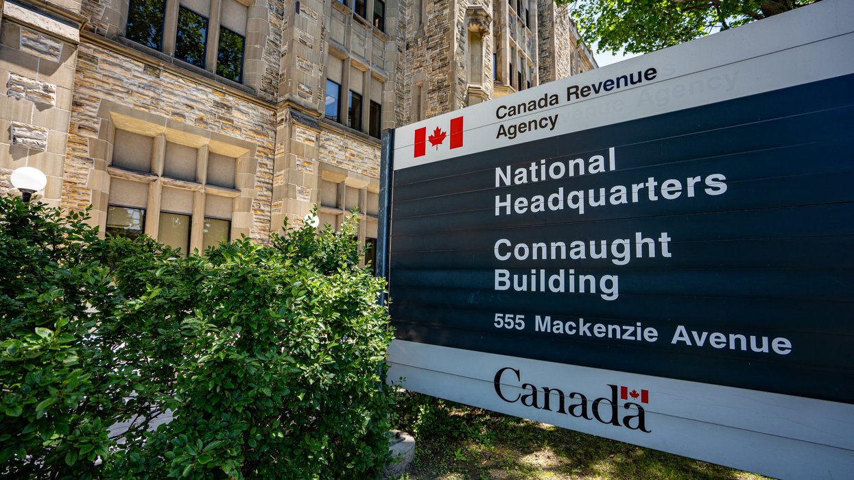 A Canada Revenue Agency National Headquarters sign outside the Connaught Building in Ottawa, with the building's stone facade visible behind it.