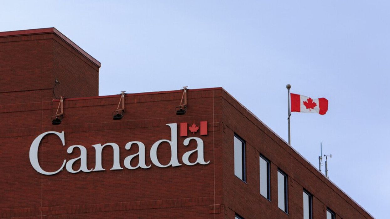 A Canadian flag and sign on a government building.