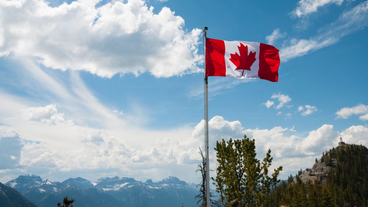 A Canadian flag waving in front of a mountain backdrop (illustrative).