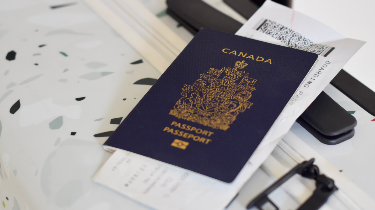 A Canadian passport and a boarding pass resting on top of a white suitcase.