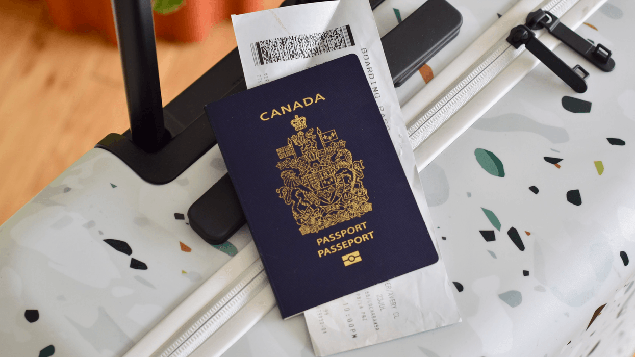 A Canadian passport and boarding pass resting on a patterned suitcase.