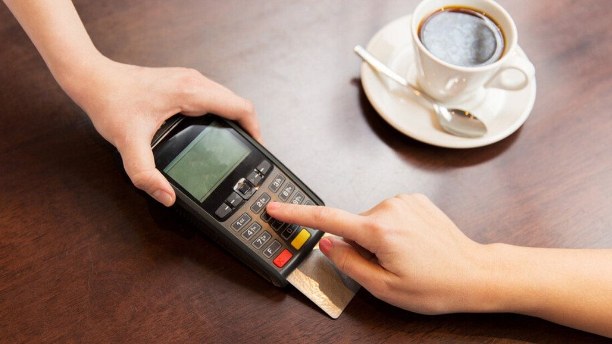 A card reader on a restaurant table as a person inserts their card.