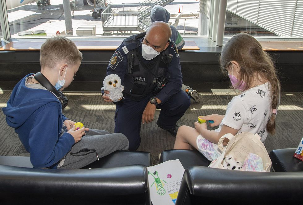 A CBSA officer gives toys to Ukrainian children arriving in Montreal.