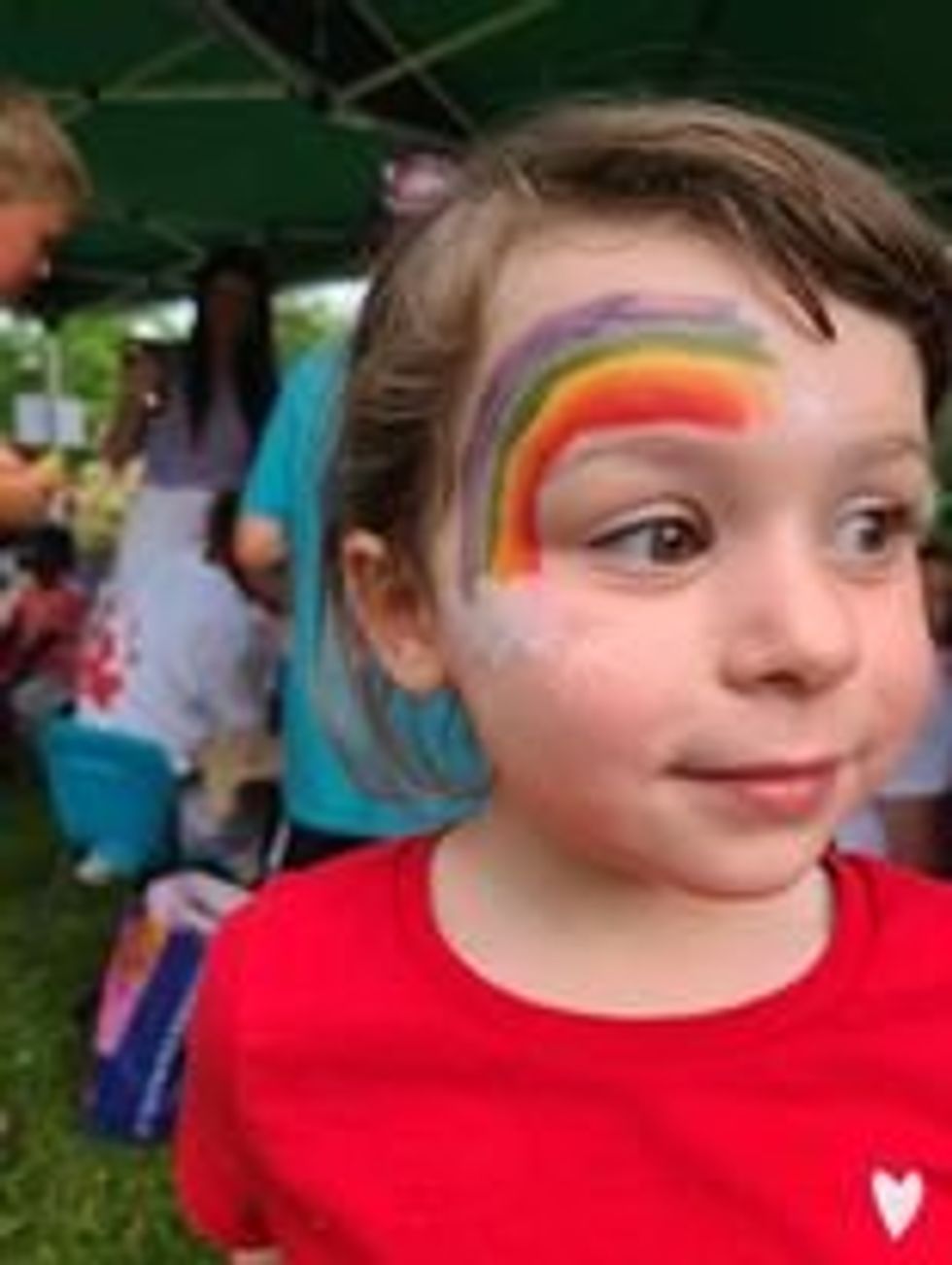 A child with rainbow face paint.