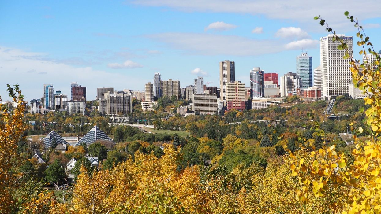 A city skyline with yellowing trees in the foreground.