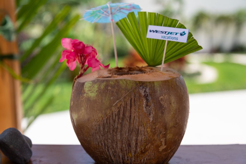A coconut with an umbrella and Westjet Vacations toothpick.