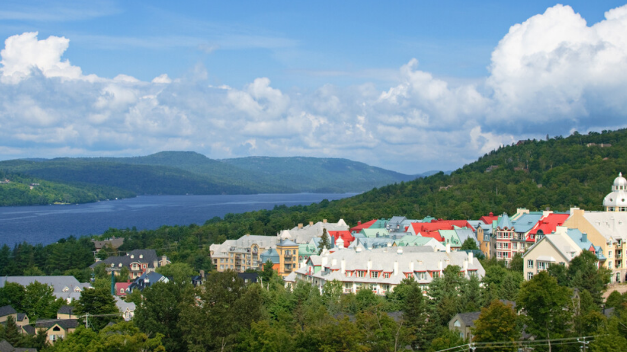 A colourful Quebec resort, surrounded by a lake and mountains, in the summer.