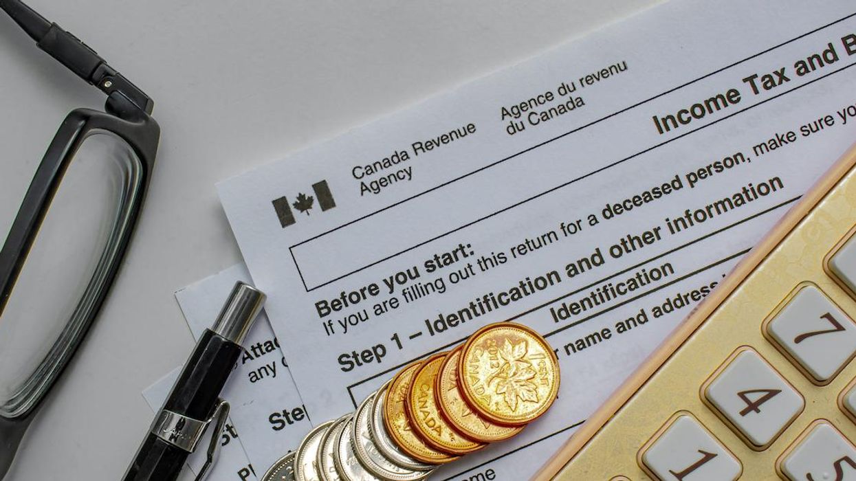 A CRA income tax declaration form on a white surface with coins, a pen, glasses and a calculator.