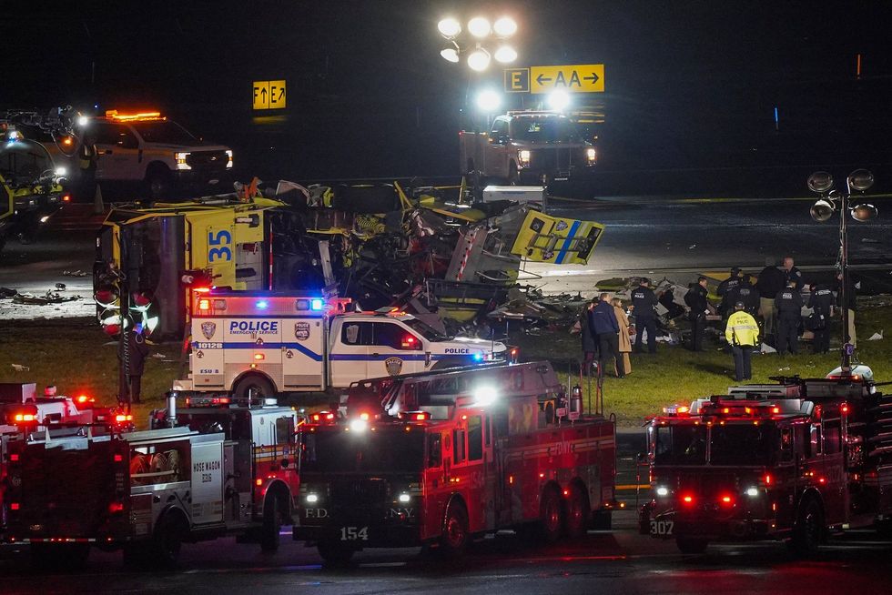 A crashed airport fire truck lays on its side on a runway.
