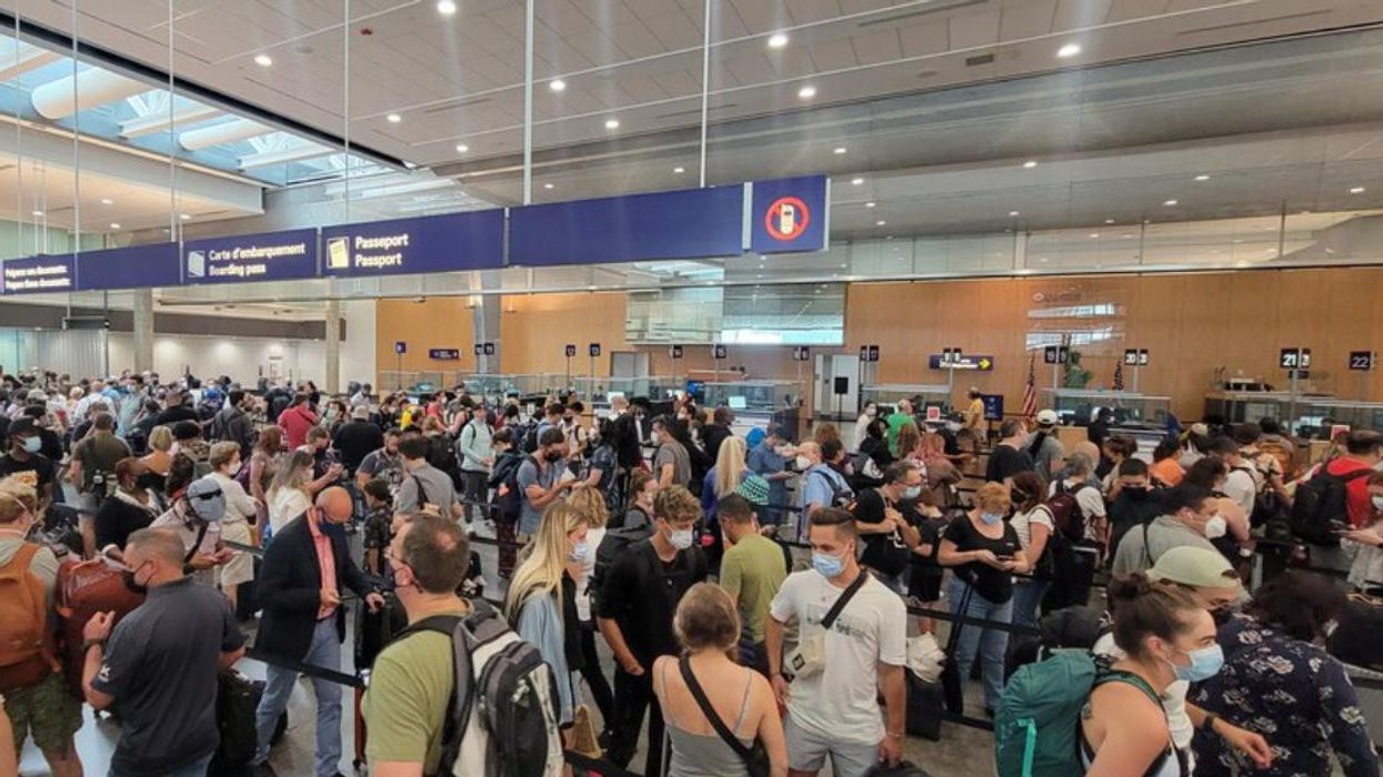 A crowd of people standing in line waiting for U.S. Customs processing at Montreal-Trudeau Airport.