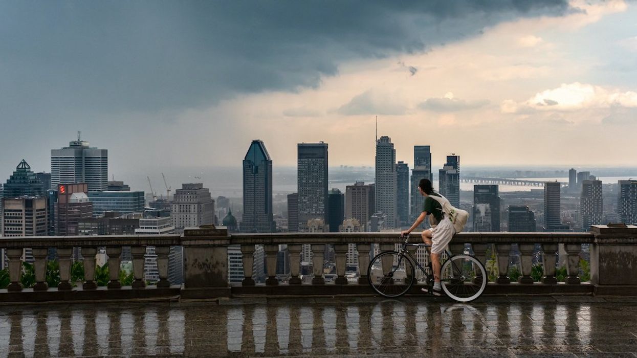 A cyclist takes in a view of the downtown Montreal skyline as seen from Mount Royal on a rainy summer day.