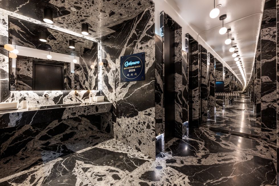 A dramatic restaurant bathroom in dark marbled stone.