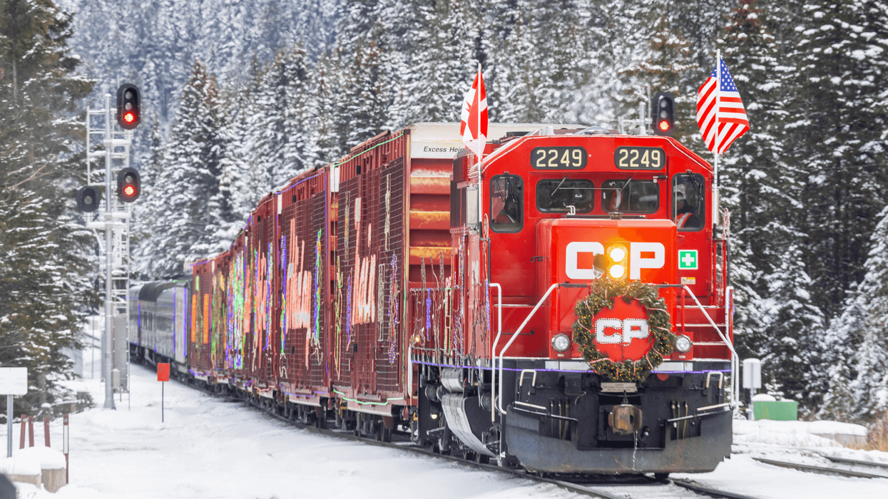 A festive red train rolling through a snowy landscape.