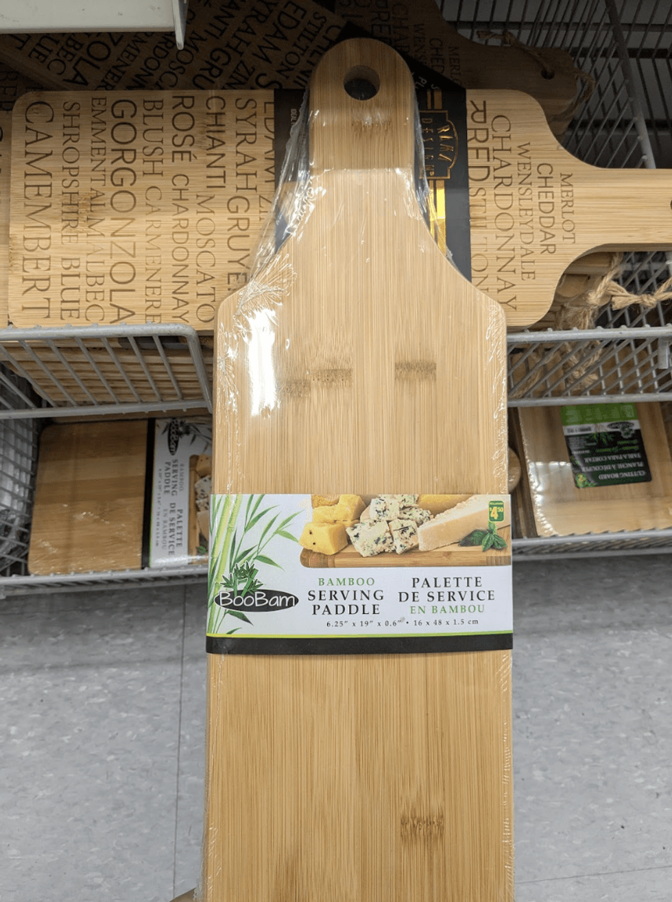 A flat rectangular bamboo serving board on a store shelf