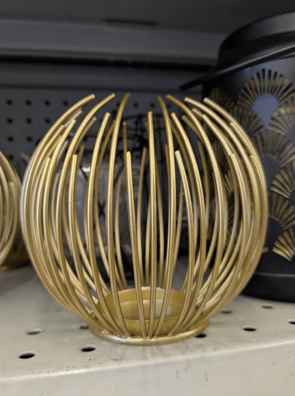 A gold wire tealight candle holder on a store shelf