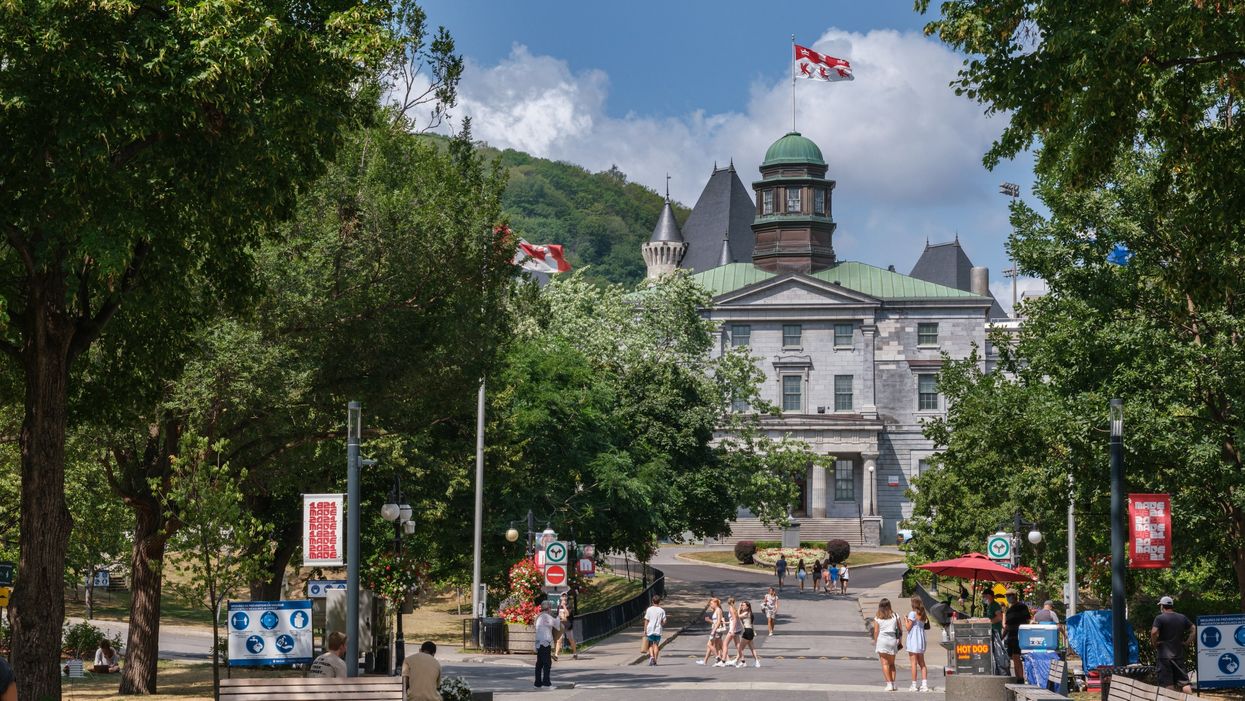 A green-roofed building with a circular driveway on an urban university campus.