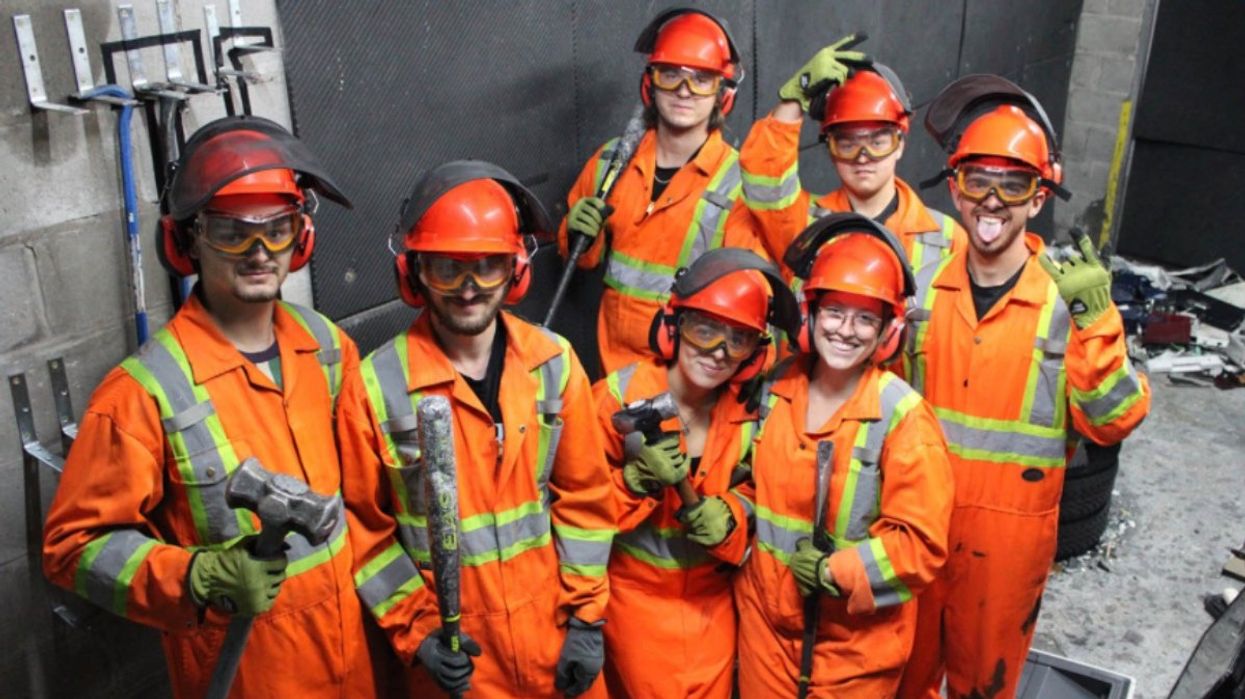A group of people wearing orange jumpsuits at a rage room in Montreal, Quebec.