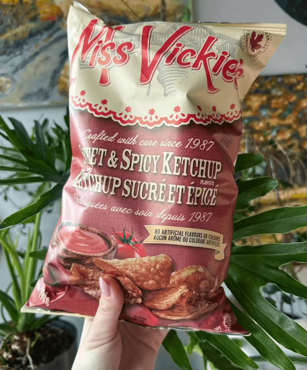 A hand holding a bag of Miss Vickie's sweet and spicy ketchup chips.