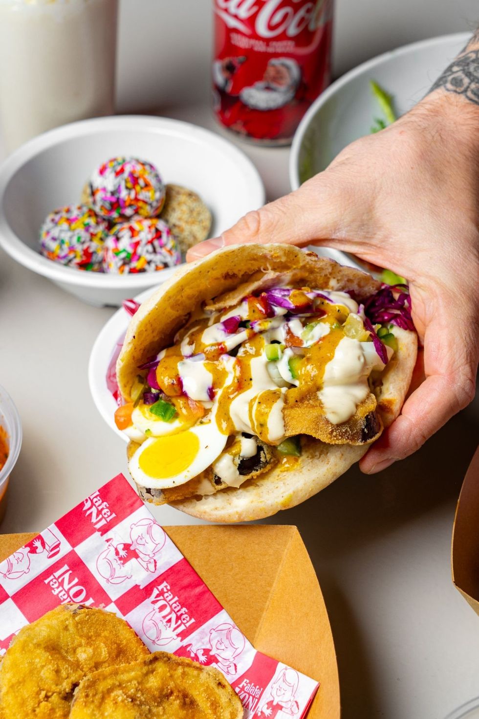 A hand holding a pita stuffed with grilled eggplants, egg, and salad.