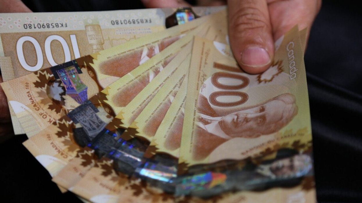 A hand holding Canadian money.