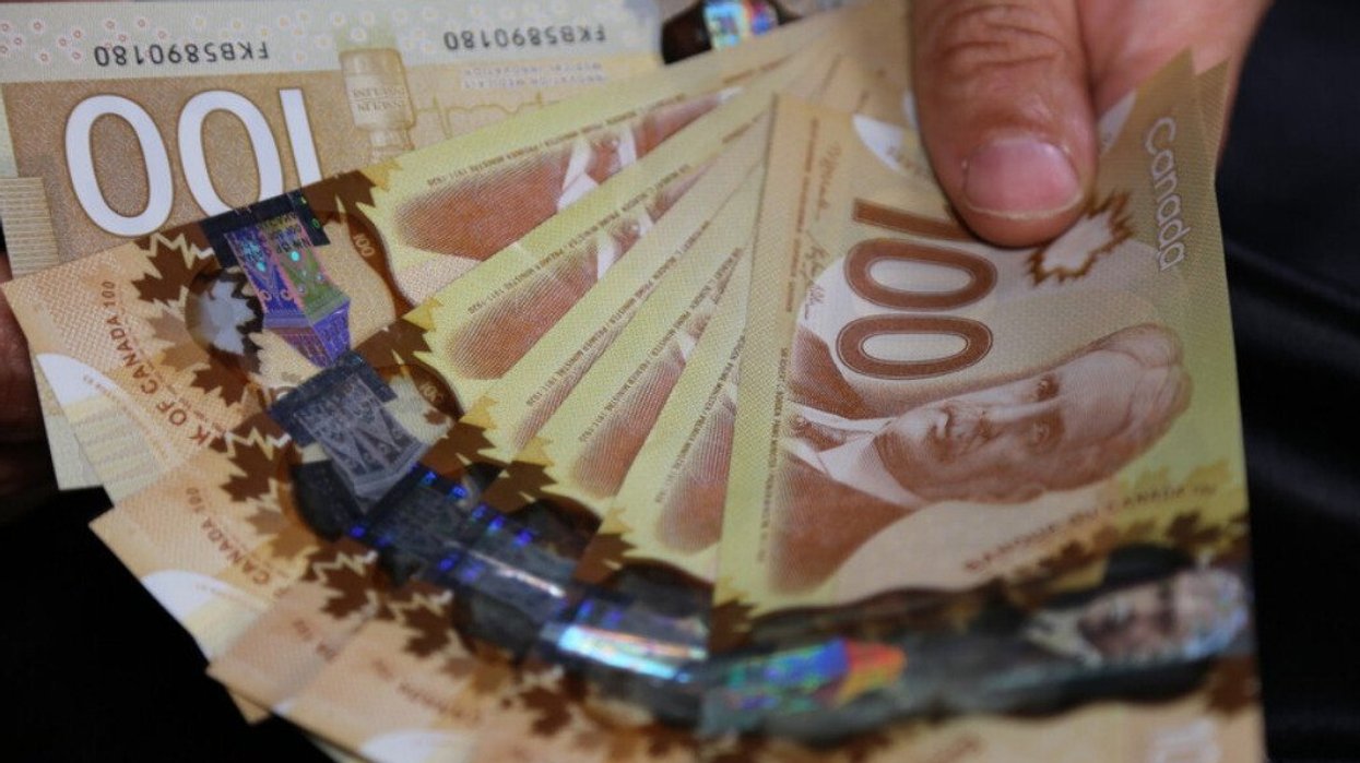 A hand holding Canadian money.