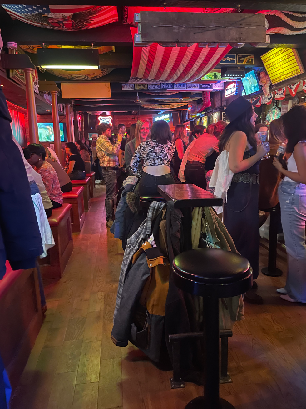 A large American flag hangs above patrons: booths to the left, tables in the centre and the bar on the right.