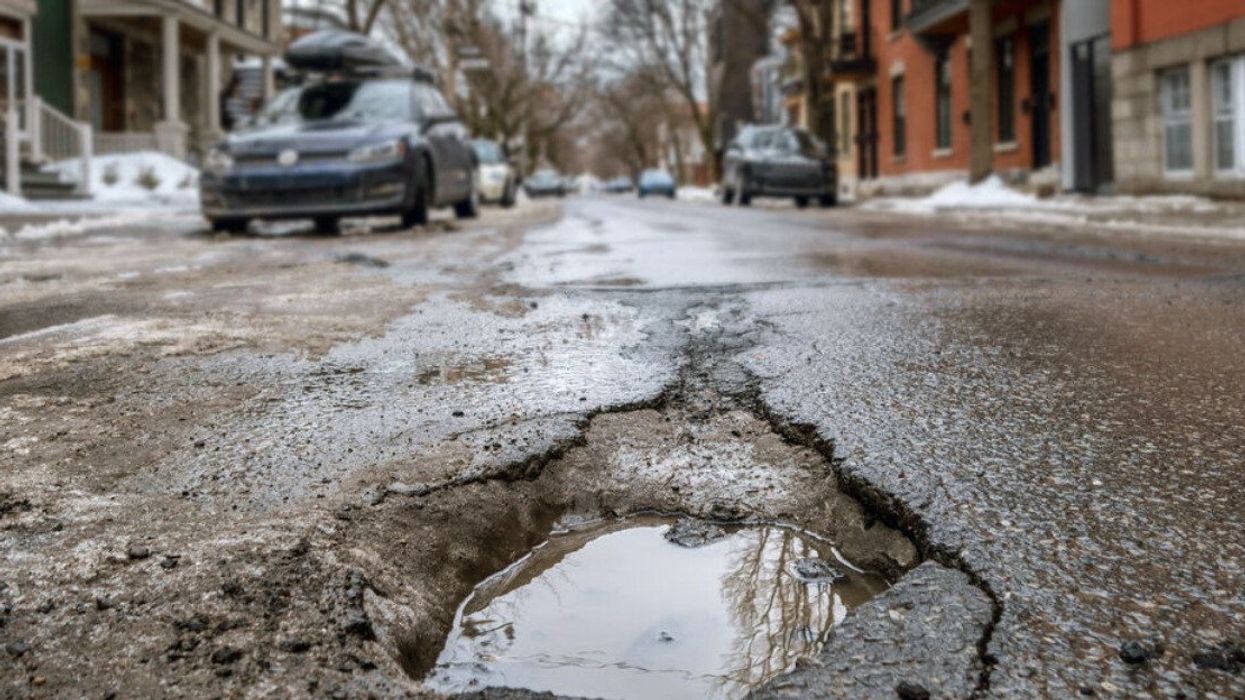 A large, deep pothole on a Montreal street during spring.