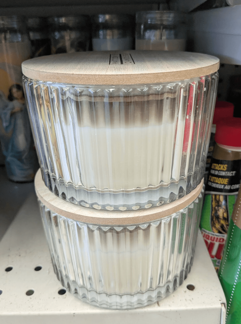 A large white ribbed candle housed in a glass container