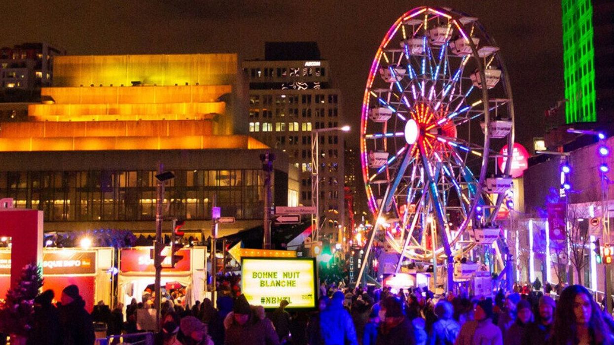 A light-up Ferris wheel in Montreal's Quartier des Spectacles, surrounded by attendees of Nuit Blanche.
