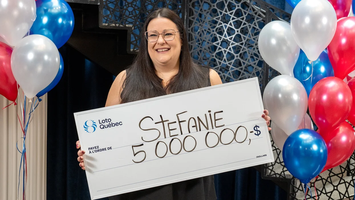 A Loto-Québec winner poses with a giant cheque.
