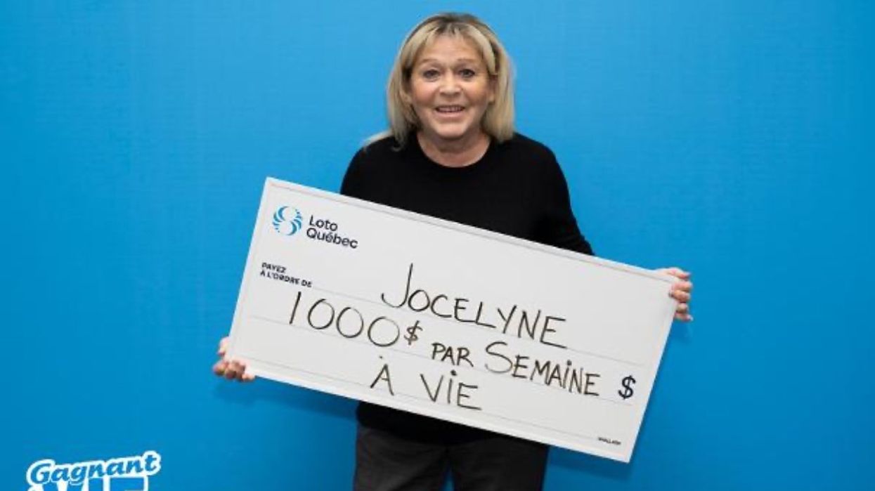 A lottery winner from Montreal posing with a giant cheque at the Loto-Québec headquarters.