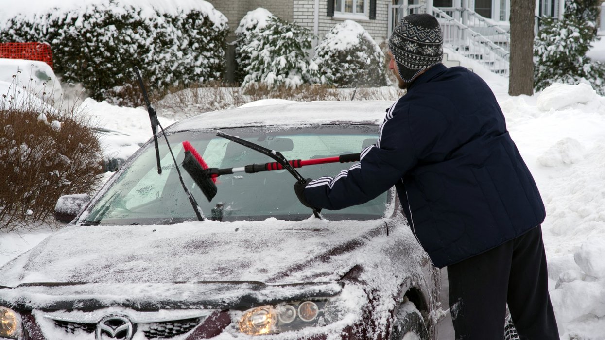 A man cleaning his car windshield after a snow storm, Montreal, Quebec, Canada