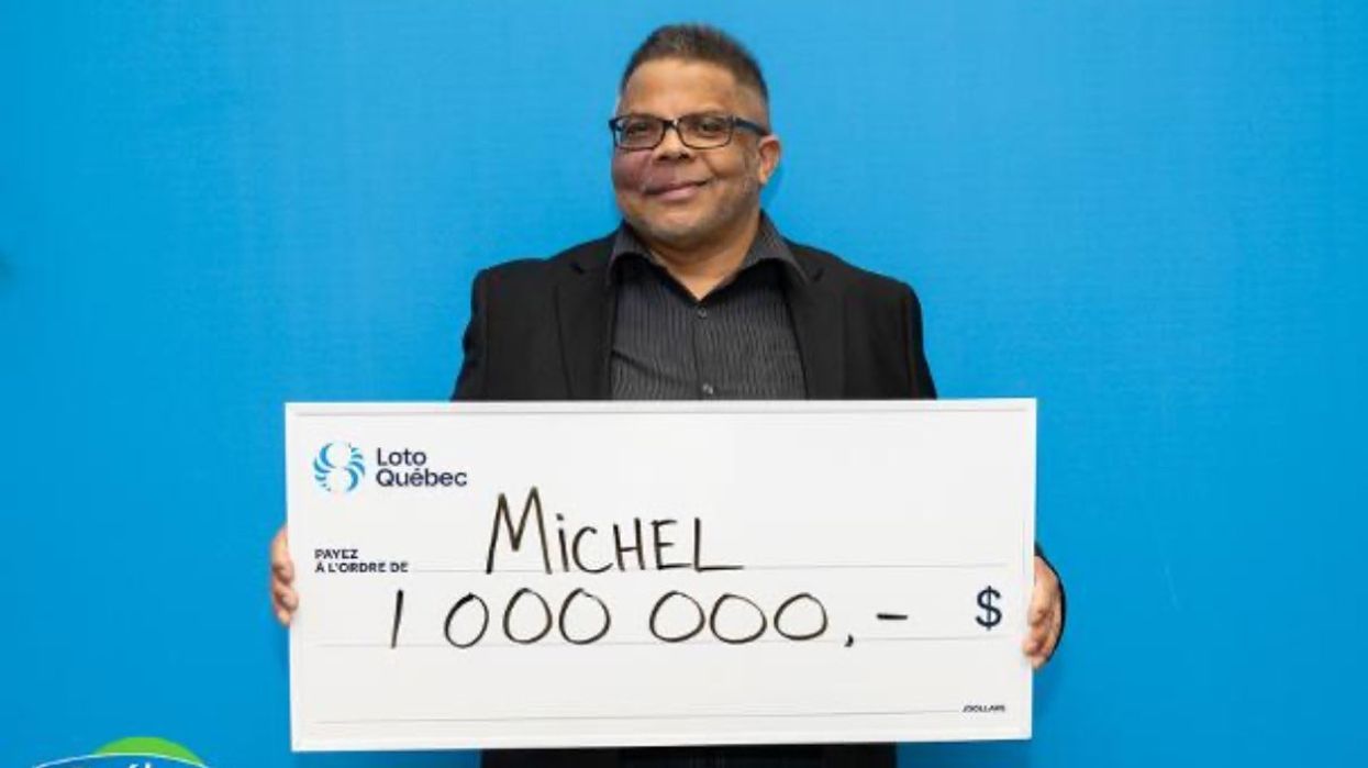 A man holding a giant cheque for one million dollars at the Loto-Québec headquarters.