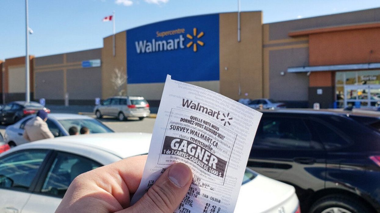 A man holding a receipt in front of a Walmart.