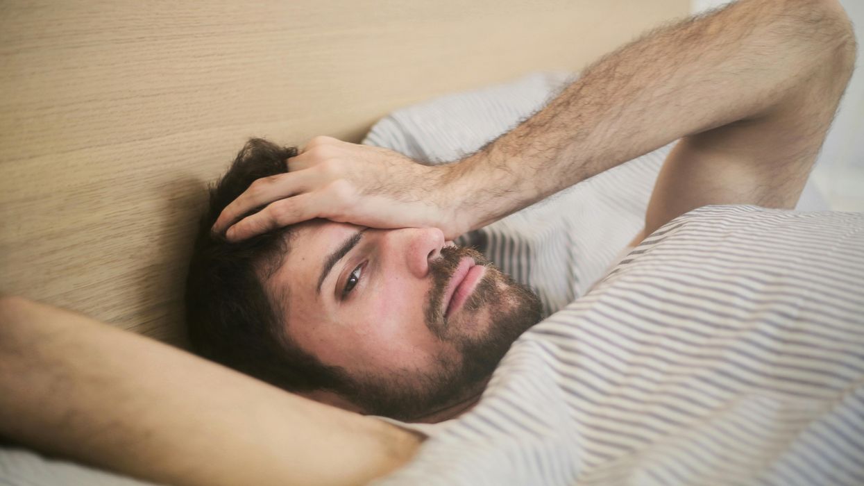 A man in bed struggling to sleep.