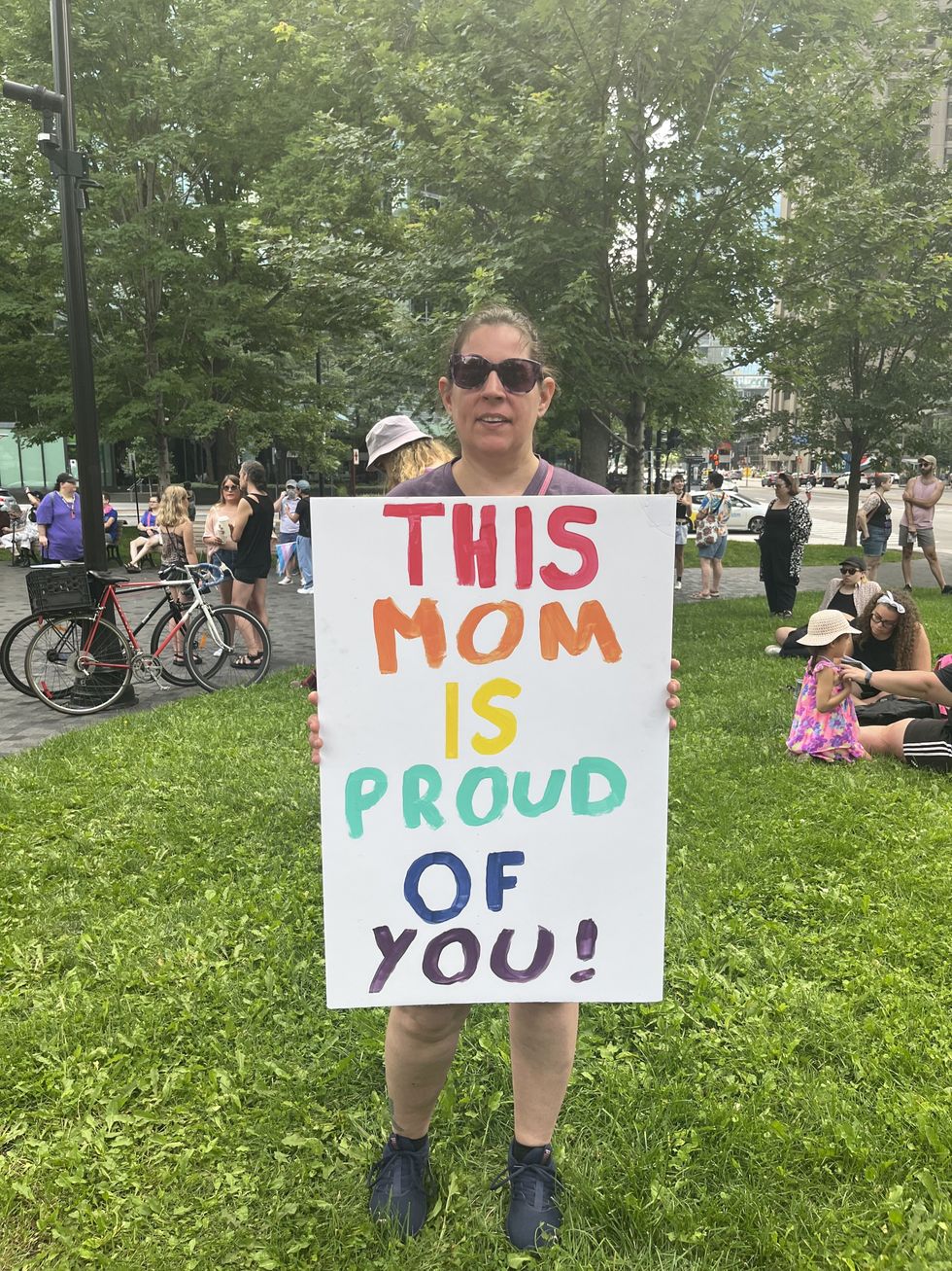 A mother attending the march holds a sign reading, "This mom is proud of you!"