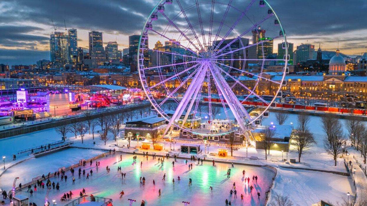 A neon-lit skating rink in Montreal's Old Port, near the Grand Roue at dusk, with a view of the city skyline.