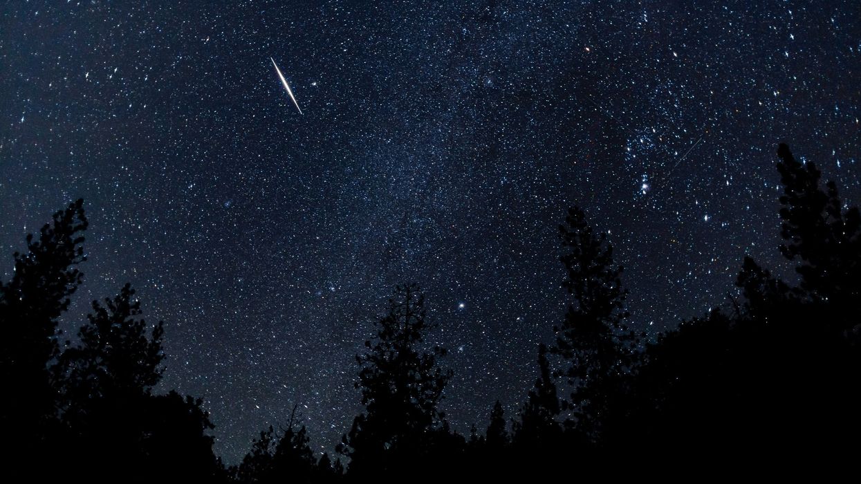 A night sky landscape with several meteors streaking across the sky.