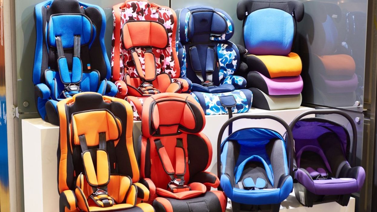 A number of colourful children's car seats stacked up in a store.