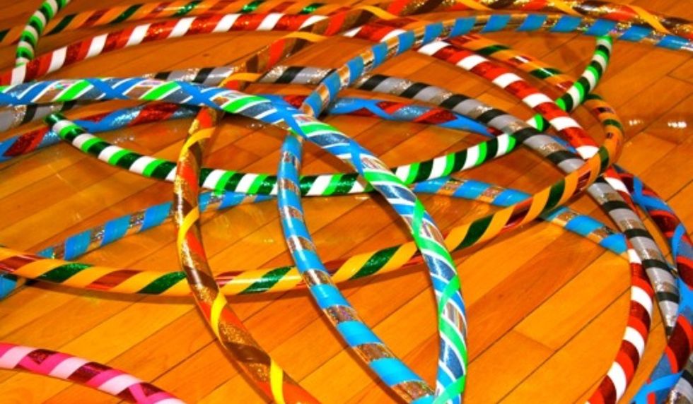 A number of hula hoops laying atop a hardwood floor.