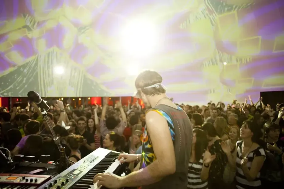 A performer plays the keyboard in front of a dancing crowd in the SATosphere.