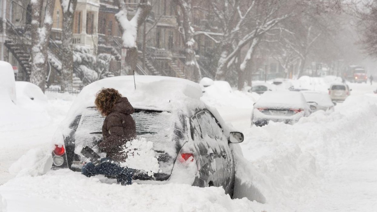 A person digging out their car during a Montreal snow storm.