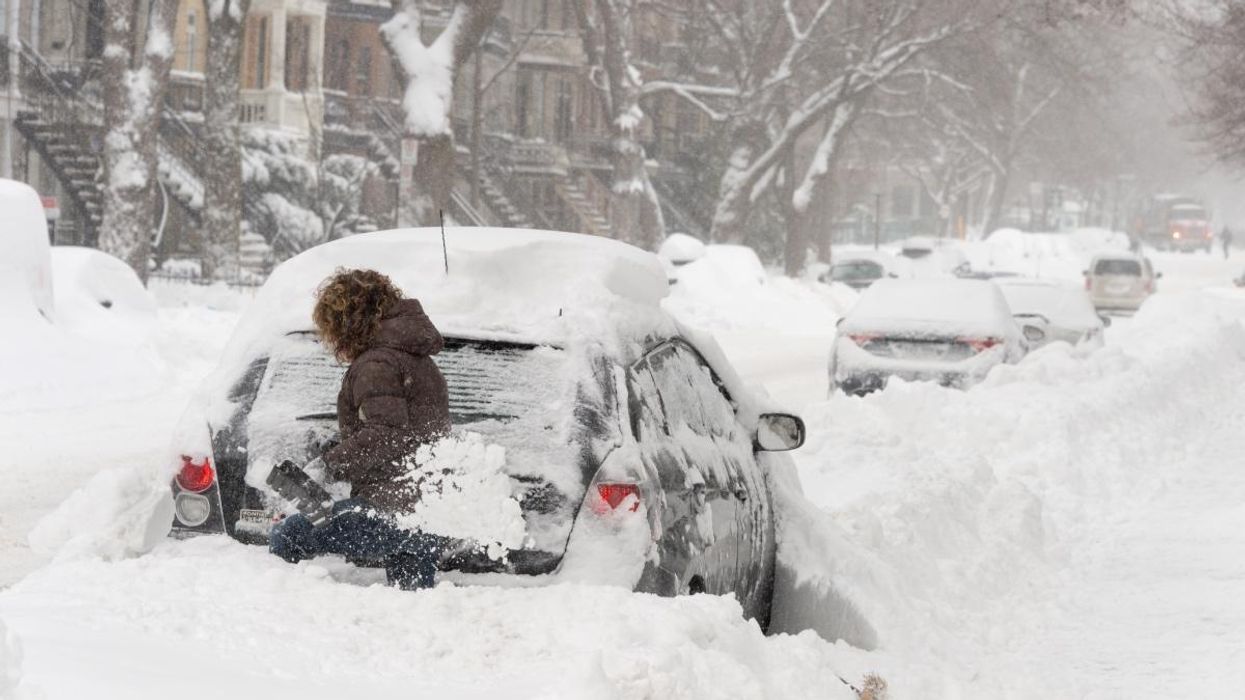 A person digging out their car during a Montreal snow storm.