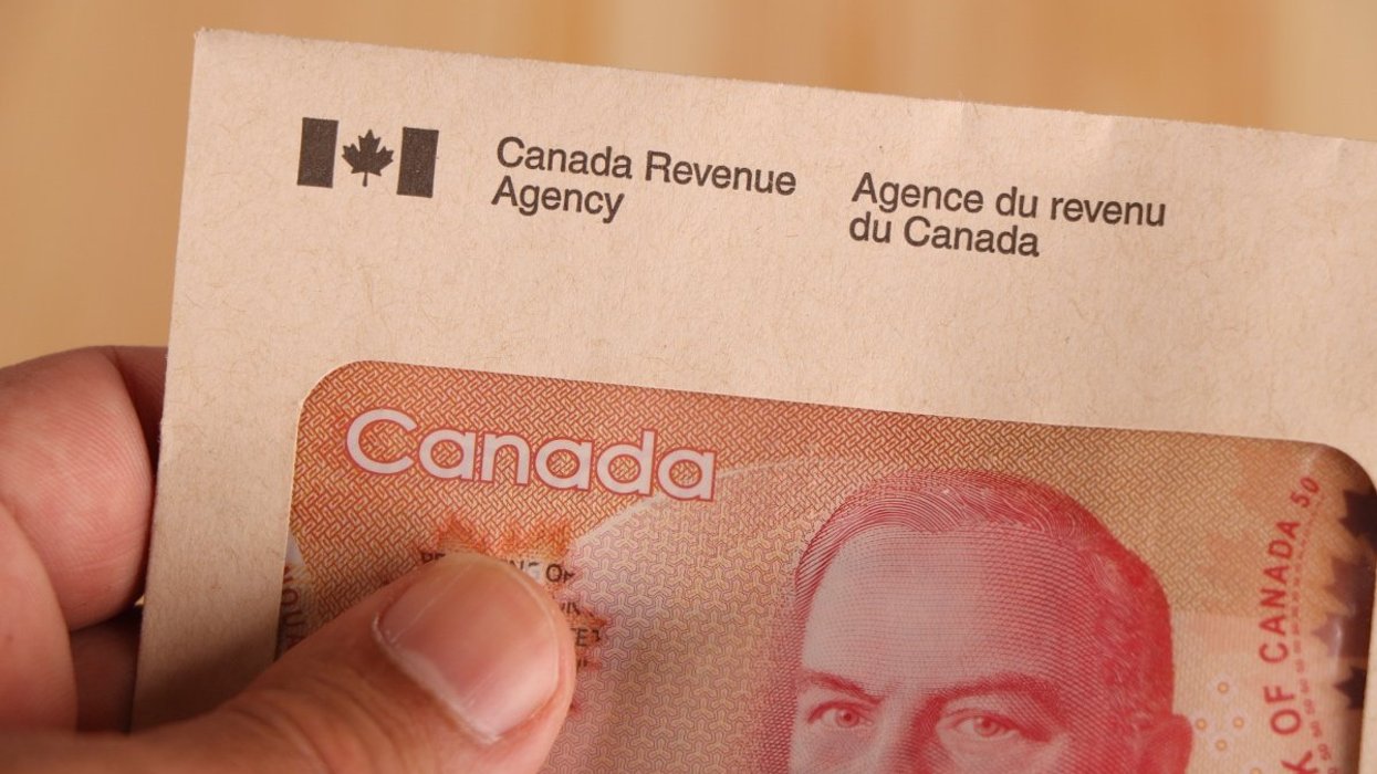 A person golding a Canada Revenue Agency-branded enveloped with a Canadian $50 bill inside.