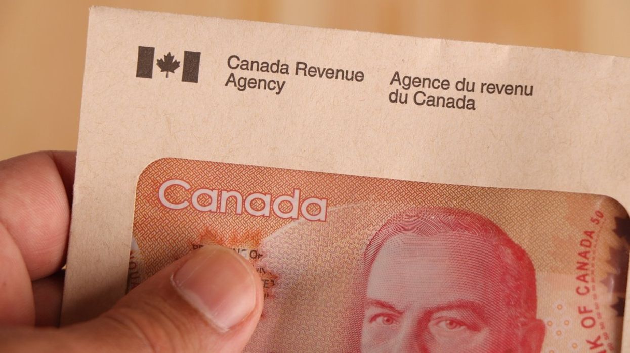 A person golding a Canada Revenue Agency-branded enveloped with a Canadian $50 bill inside.