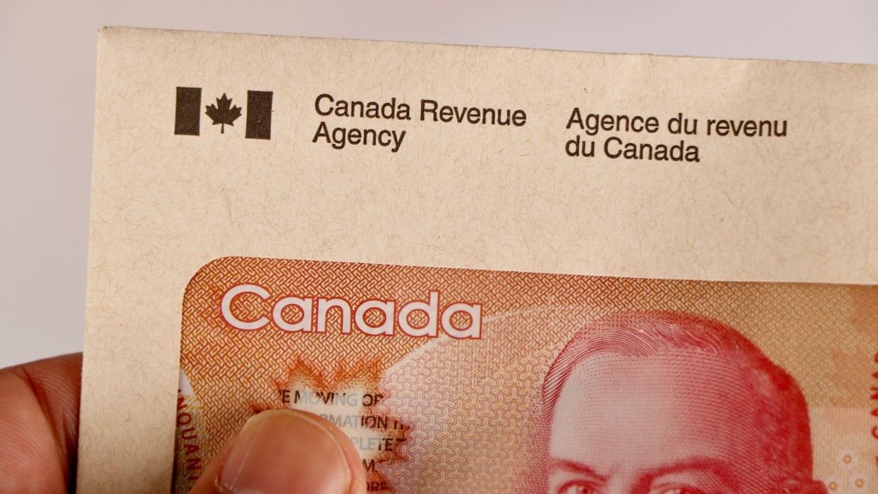 A person holding a Canada Revenue Agency envelope with a Canadian $50 bill inside.