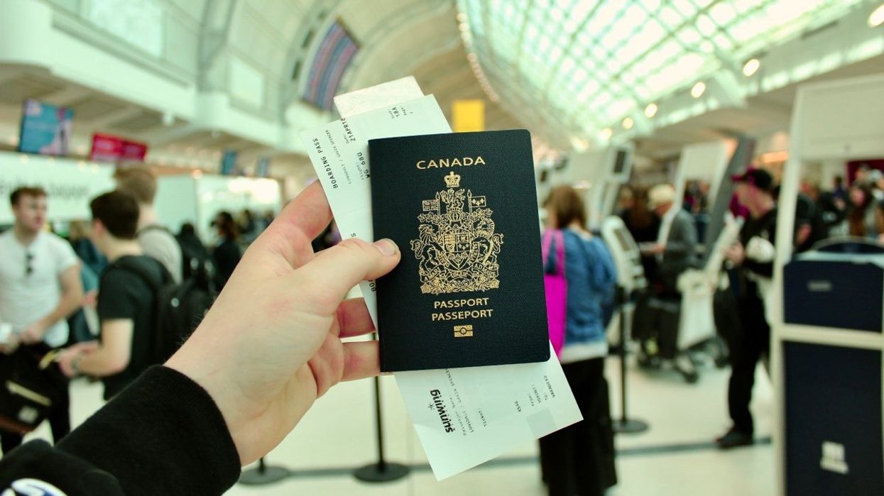A person holding a Canadian passport and boarding pass inside of an airport.